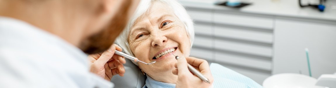 Senior woman smiling at her dentist with dental implants in West Orange