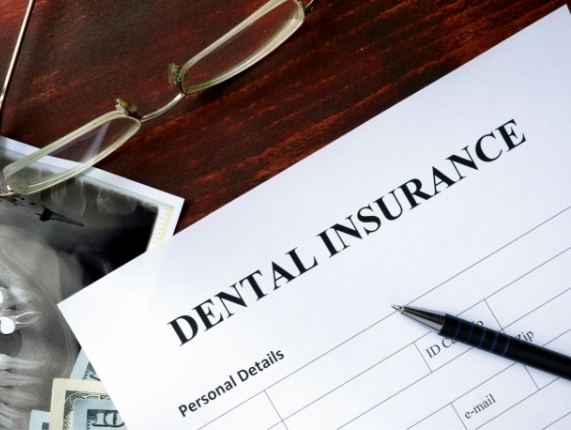 Dental insurance paperwork on dark wood table