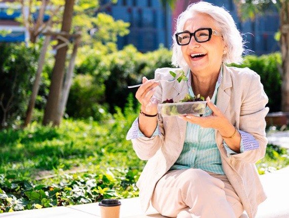 Lady smiles while eating salad