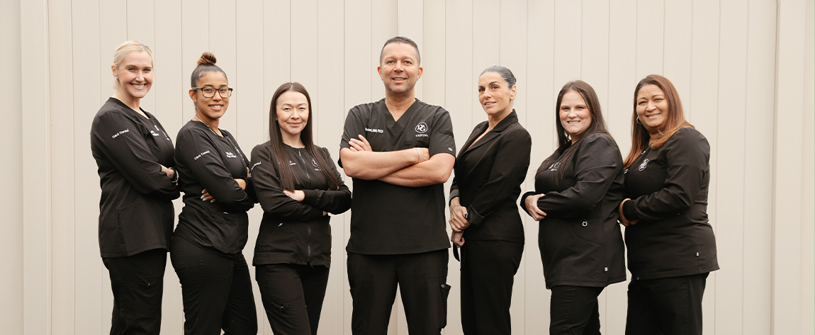 West Orange dental team standing in a line in black scrubs with their arms crossed