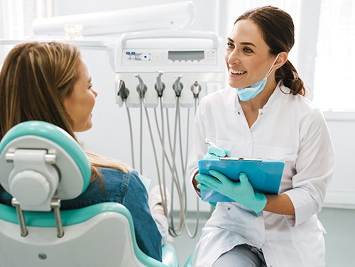 Dentist smiling while taking notes on clipboard