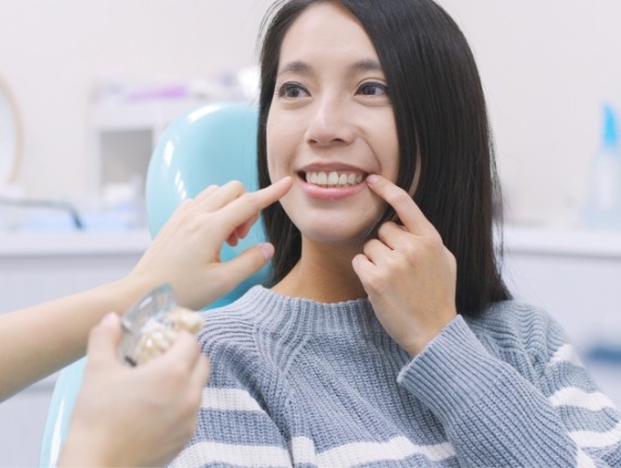 Young woman pointing to her smile during dental checkup in West Orange