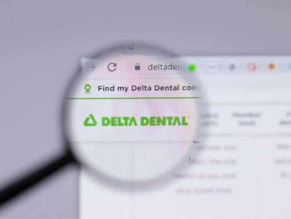 Magnifying glass over Delta Dental insurance logo on computer screen