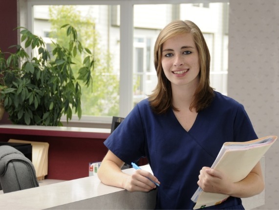 Smiling dental team member leaning against front desk