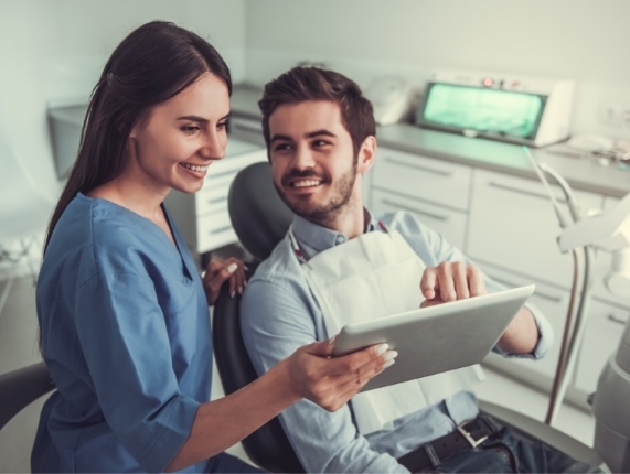 Dental patient and dental assistant looking at tablet screen together