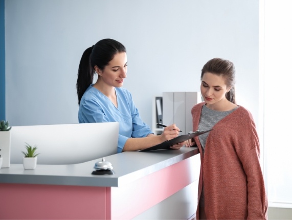 Dental team member showing a clipboard to a patient