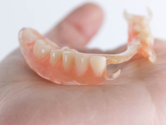 Person holding a partial denture in their hand