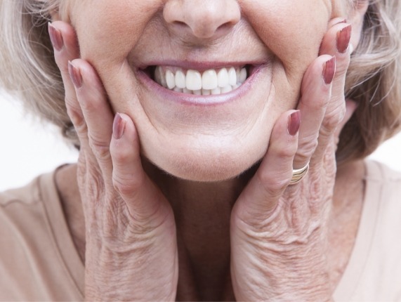 Close up of smiling senior woman touching both of her cheeks