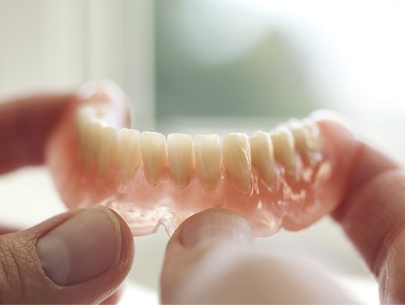 Close up of hands holding a full denture