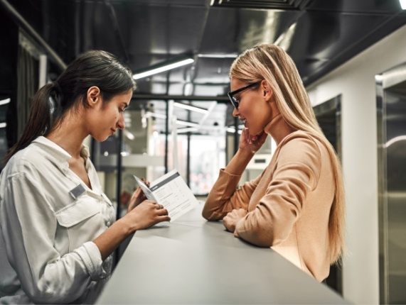 Woman talking to dental team member at front desk