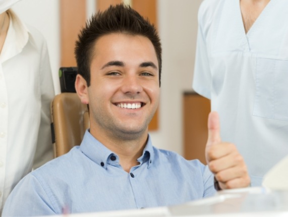 Smiling man giving thumbs up in dental chair