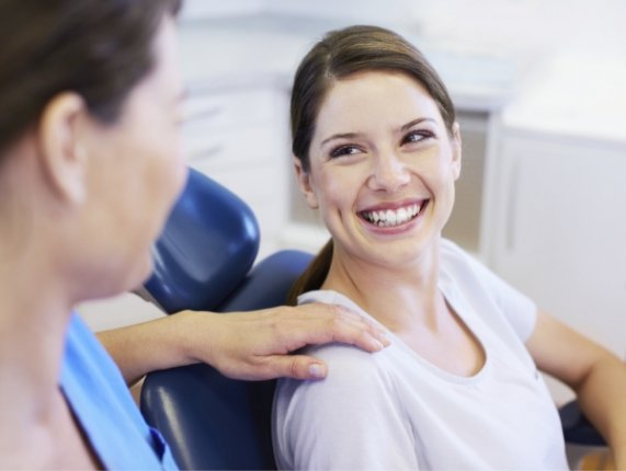 Smiling woman in dental chair talking to her dentist