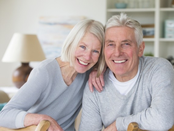 Senior man and woman in gray sweaters sitting in their living room