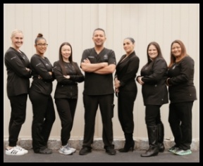 West Orange dental team members in black scrubs standing in a line with their arms crossed