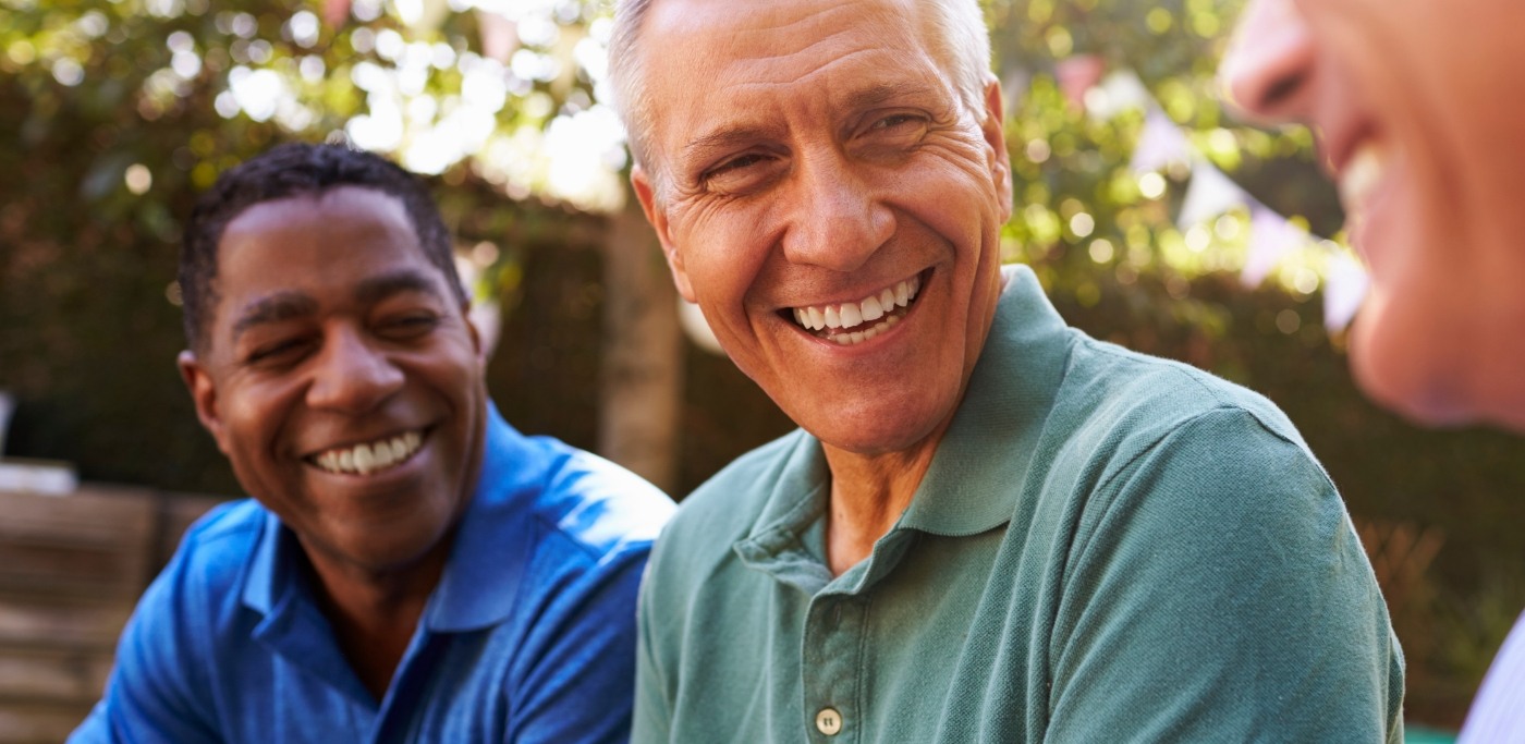 Three men laughing together outdoors on sunny day