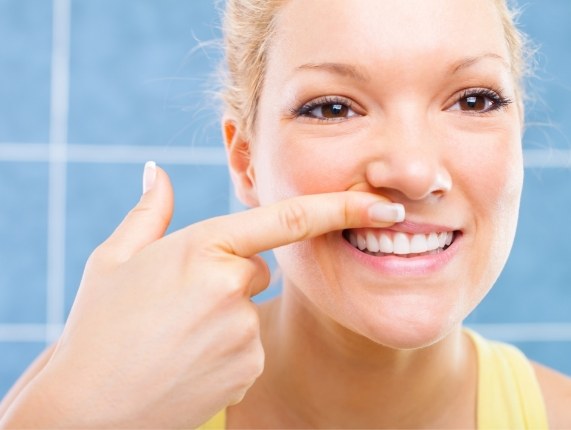 Young woman looking at her gums in mirror