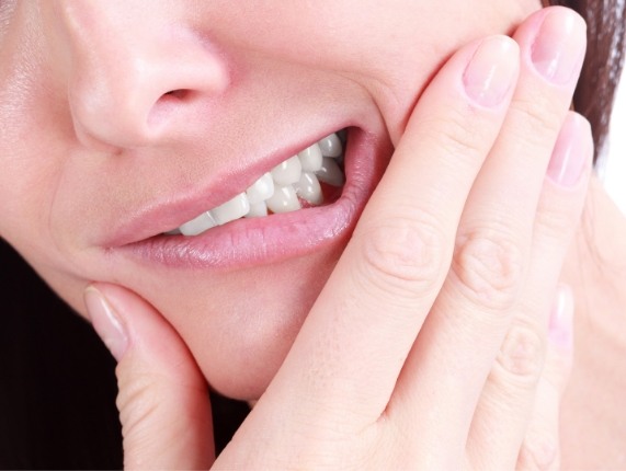 Close up of person holding their jaw in pain before tooth extraction in West Orange