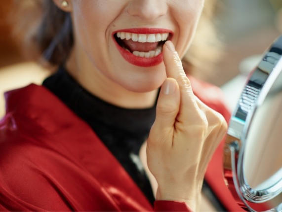 Woman with red lipstick looking at her mouth in mirror