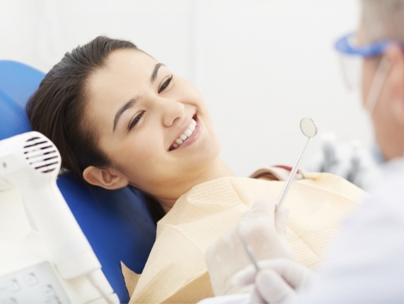 Young woman in dental chair smiling at her dentist