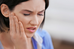 Close-up of a woman with pain on one side of her jaw