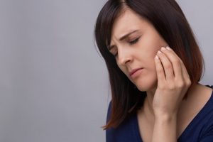 A woman holding her cheek in pain