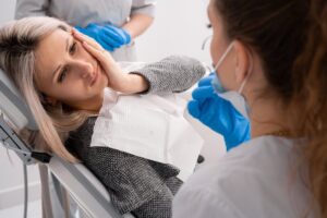 Woman in the dentist's chair holding her mouth in pain. 