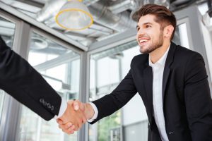 Two young businessmen shaking hands in office
