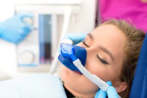 Patient receiving nitrous oxide in dentist’s chair with eyes closed.